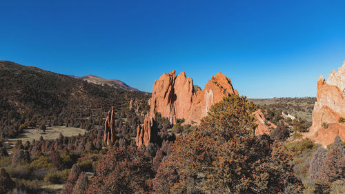 Panoramic view of rocks and trees against blue sky