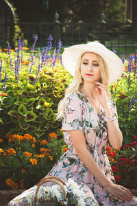 Beautiful young woman sitting against plants