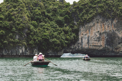 People in boats on lake against trees