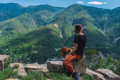 Man sitting on mountain looking at mountains