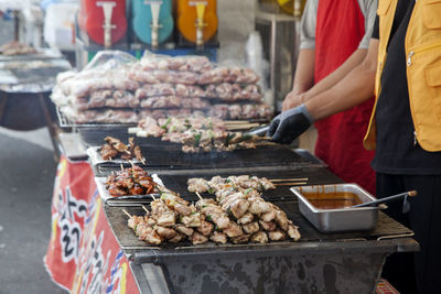 Midsection of people cooking food at market for sale