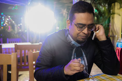 Young man using mobile phone while sitting on table