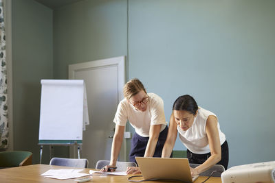 Women in boardroom using laptop