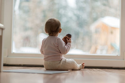 Rear view of baby girl looking through glass door at home