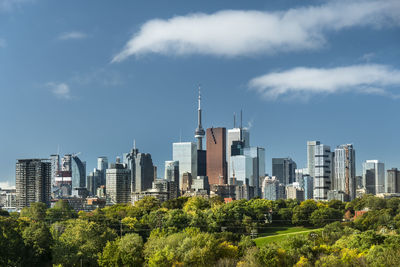 Plants growing by modern buildings against sky in city