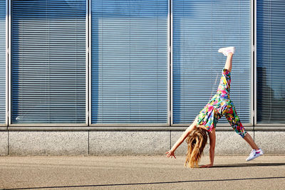 Upside down image of girl by wall outdoors