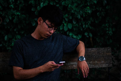 Young man using mobile phone while sitting outdoors