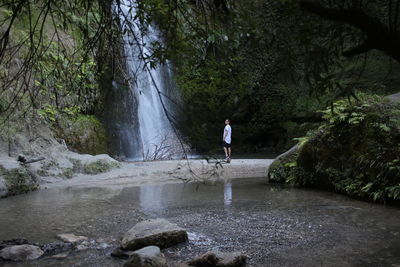 Man and woman walking on river in forest