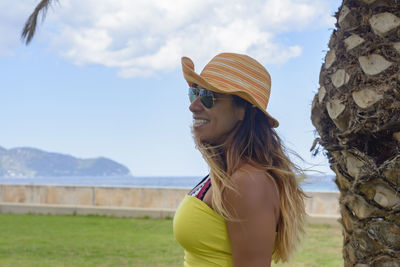 Portrait of a latin woman smiling, on vacation in mallorca under a palm tree, hollidays concept