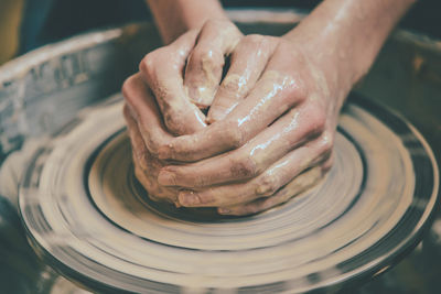 Master potter folded together hands sculpts a clay product on a potter's wheel. 