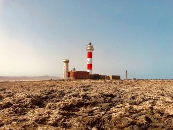 Lighthouse on beach against sky