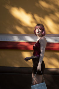 Portrait of young woman standing against window