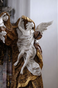 Statue of angel against white wall