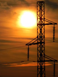 Silhouette cranes against sky during sunset