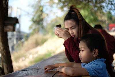 Mother with thoughtful son at railing against trees