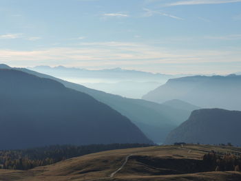 Aerial view of country road along mountainous landscape against cloudy sky