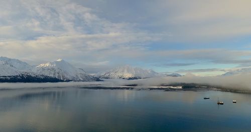 Scenic view of lake by snowcapped mountains against sky