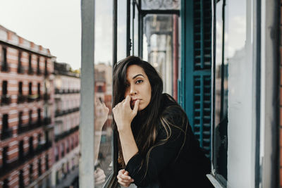 Lonely young woman leaning on glass window