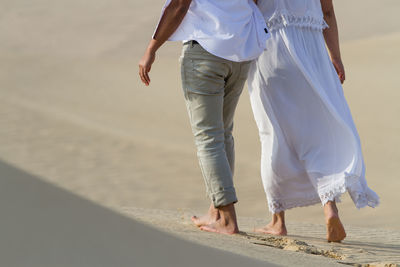 Low section of two people on sand