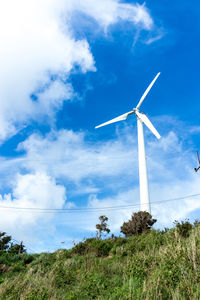 Low angle view of windmill on field against blue sky
