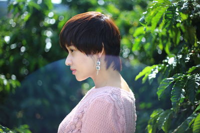 Side view of young woman by plants