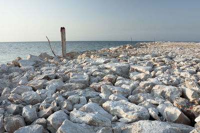 Rocks by sea against clear sky