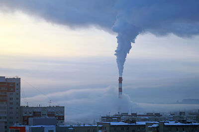 Smoke emitting from chimney against sky