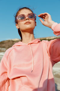 Portrait of young woman wearing sunglasses standing at beach