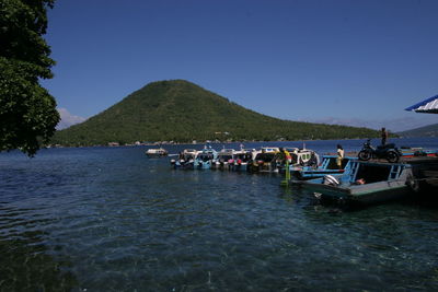 Boats moored in sea against clear sky