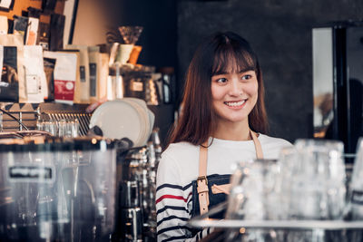 Smiling barista looking away while working in cafe