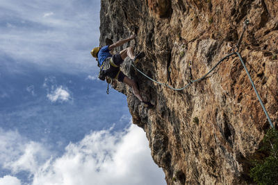 Low angle view of man climbing on rock