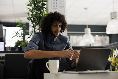 Portrait of young woman using laptop at office