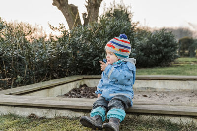 Full length of boy sitting by plants