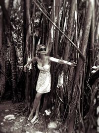 Full length of young woman standing in forest