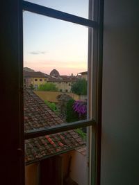 Scenic view of house seen through window at sunset