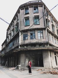 Woman standing by building against sky in city