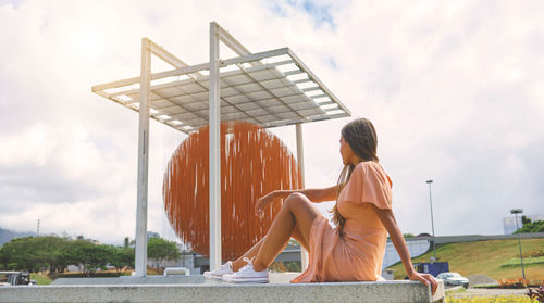 Rear view of woman sitting on retaining wall