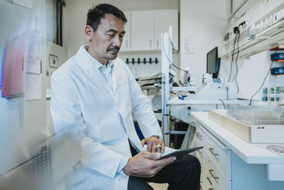 Male scientist using digital tablet while sitting at laboratory