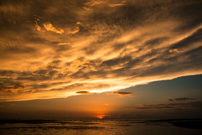 Scenic view of sea against dramatic sky during sunset