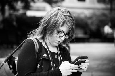 Close-up of young woman using mobile phone outdoors