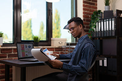 Side view of young man using laptop at office