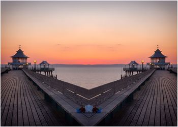 Pier over sea against sky during sunset