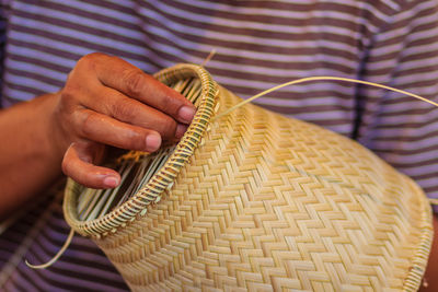 Midsection of man making wicker decoration