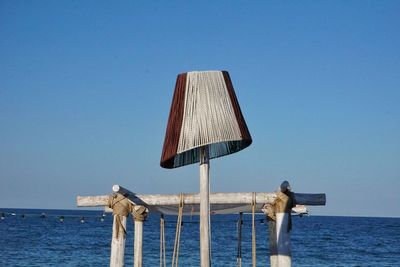 Lifeguard hut on sea against clear blue sky