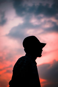 Portrait of silhouette woman standing against orange sky