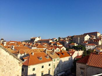 High angle view of houses in town against clear blue sky