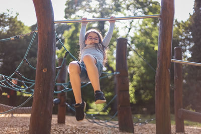 Portrait of a beautiful caucasian girl is doing push-ups on the horizontal bar in the the playgroun