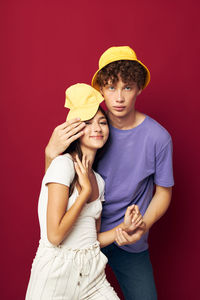 Portrait of young coupe embracing against maroon background