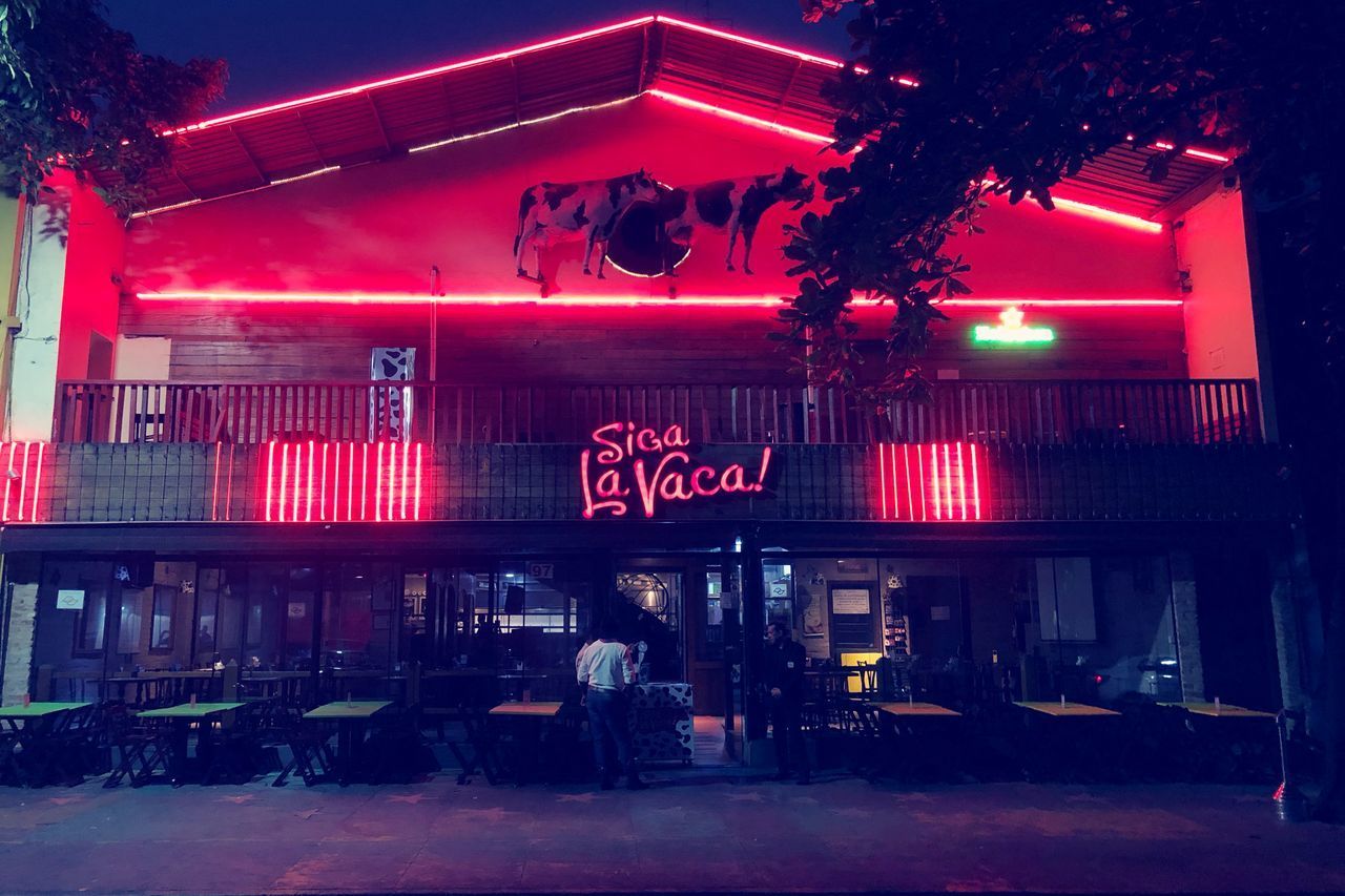 ILLUMINATED BUILDING BY STREET AT NIGHT