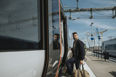 Side view of man with luggage entering in train at station